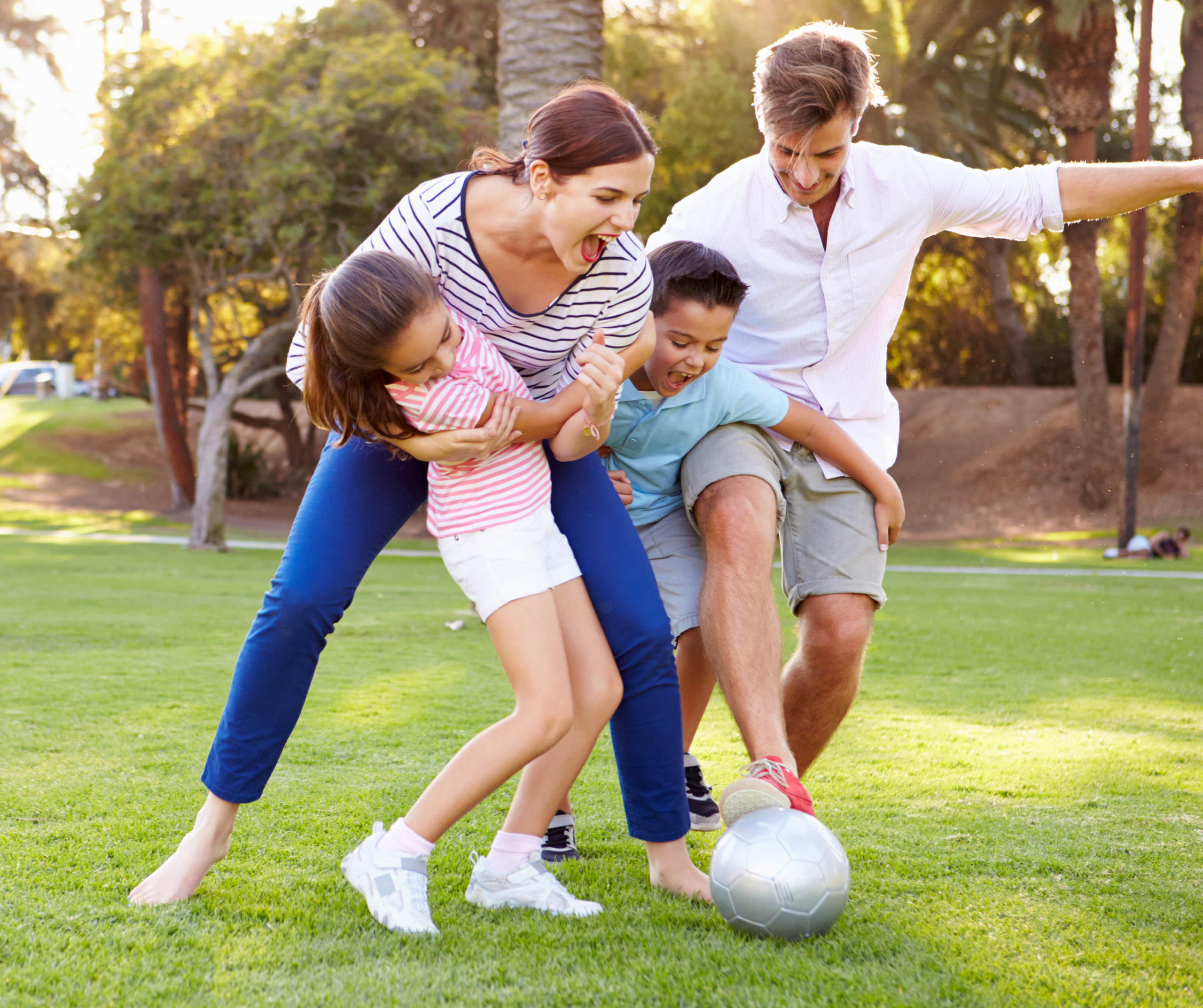 Family playing football in a green park inside a residential township