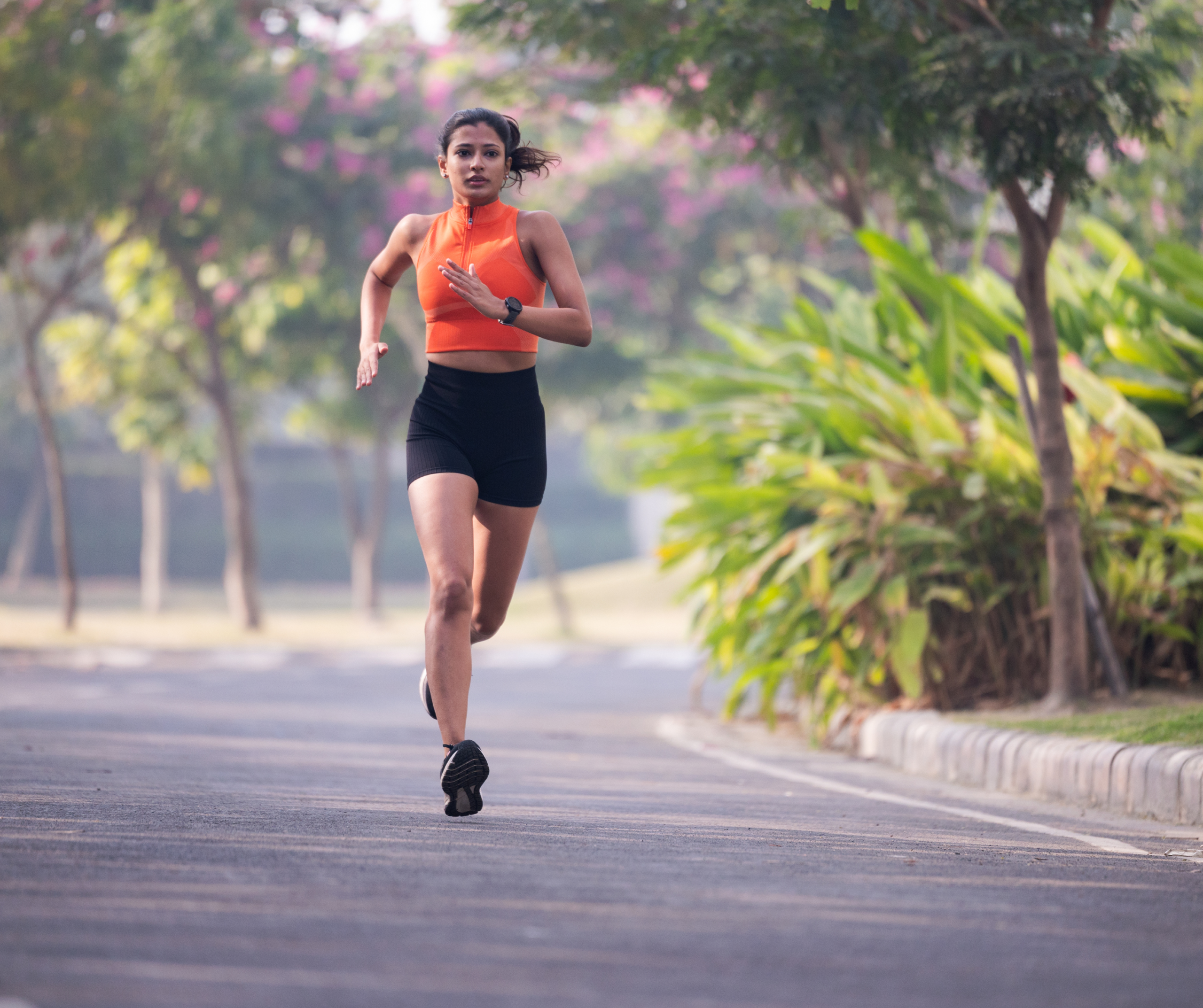 Woman jogging on a tree-lined road within a gated residential community