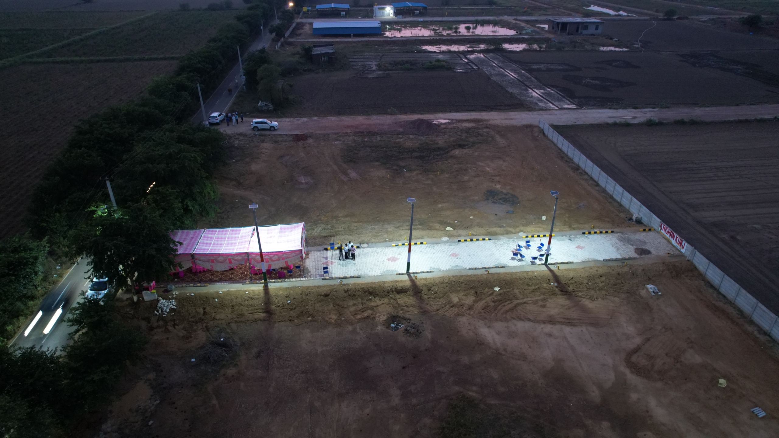 Aerial evening view of Krishan Kunj residential plots with illuminated site office