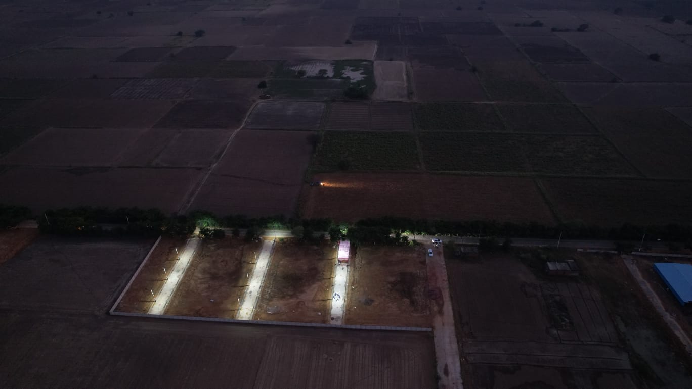 Night view of plotted development site with street lights and surrounding farmland in Jhajjar